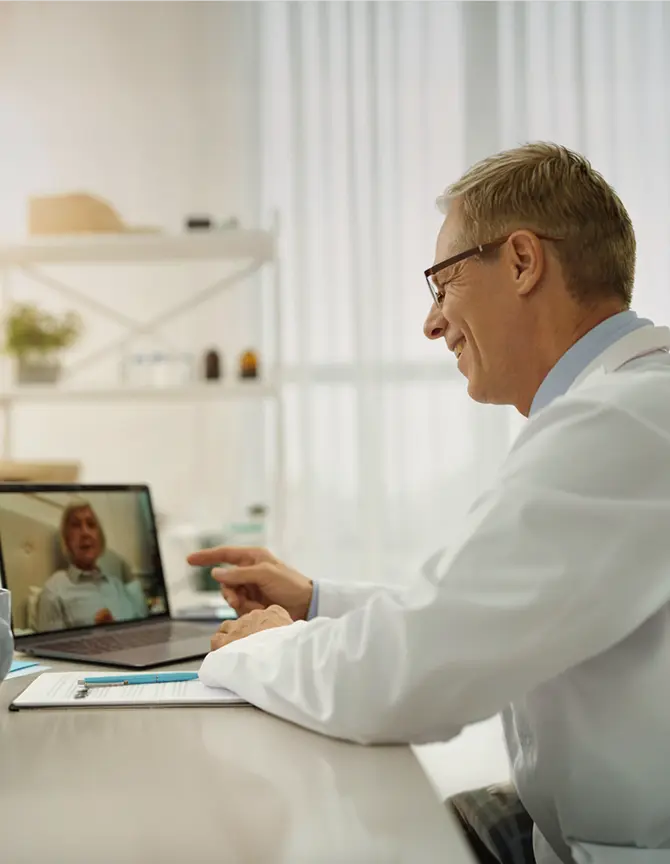 Doctor consulting with a patient through a video call on a laptop.