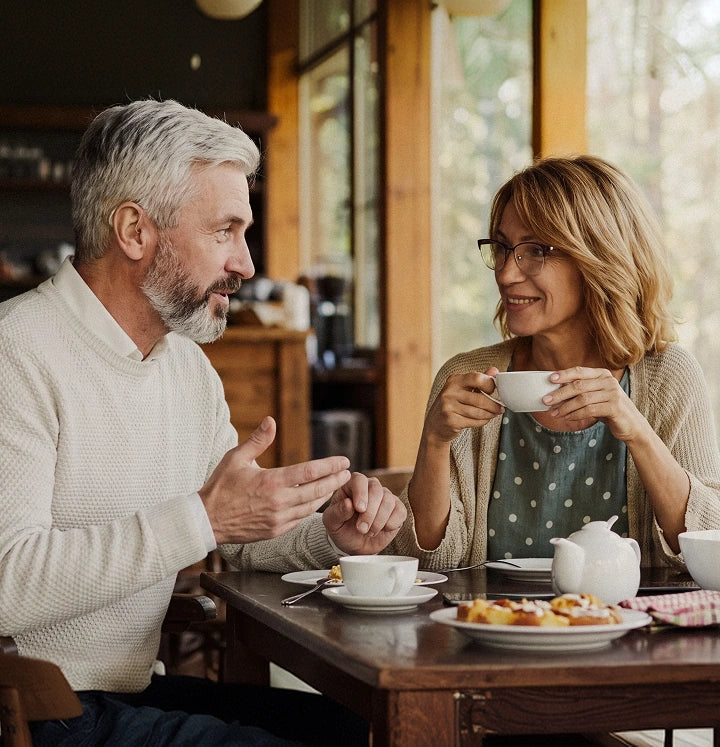 Hearing health awareness with an older couple enjoying a conversation over coffee.