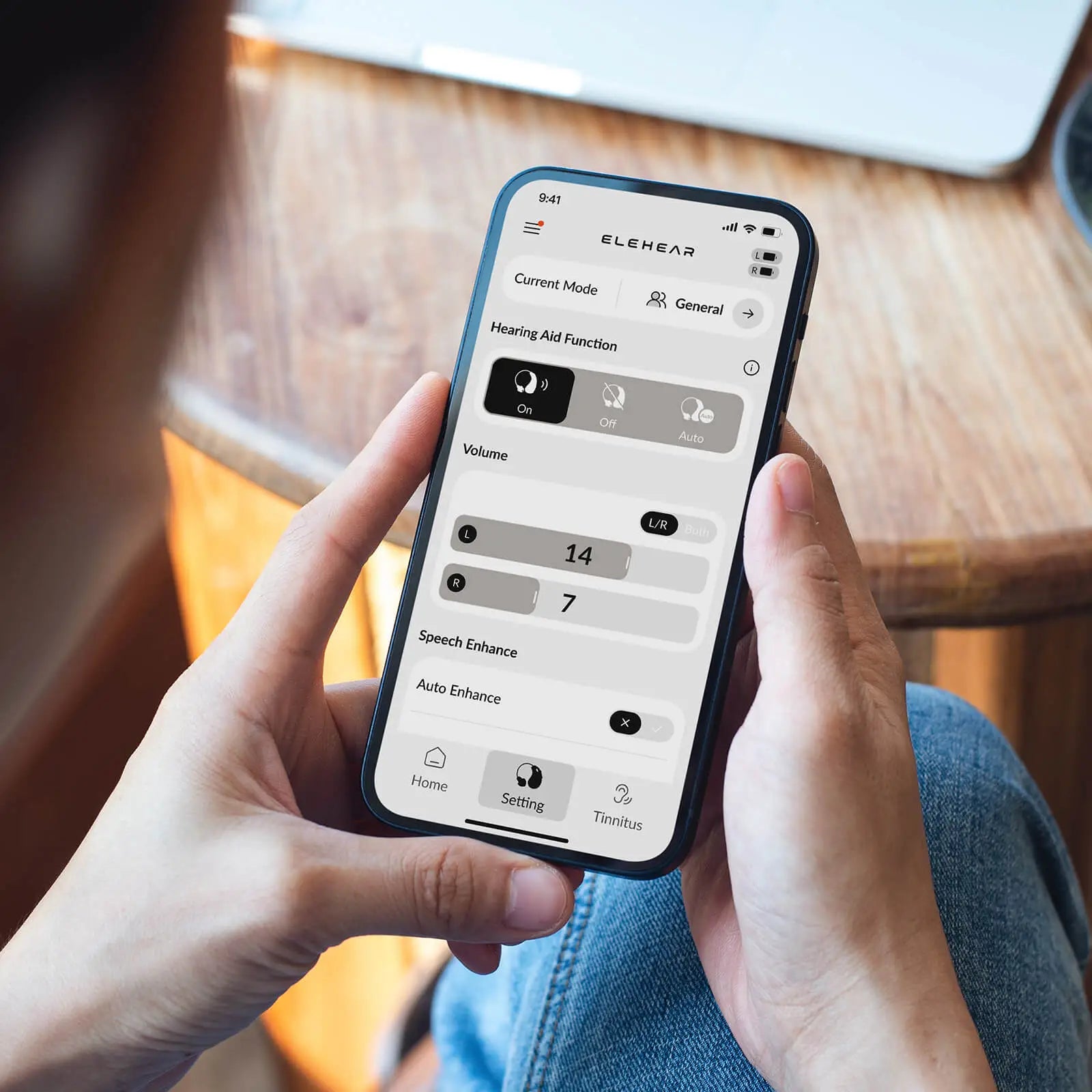 Person adjusting hearing aid volume and settings on ELEHEAR smartphone app with customizable sound modes