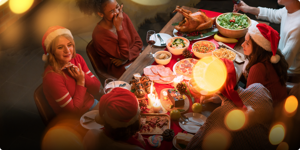 People celebrating Christmas with a festive meal, wearing Santa hats, around a table with decorations.