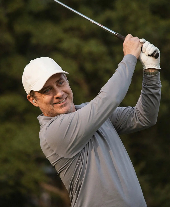 Man swinging a golf club with a blurred green background