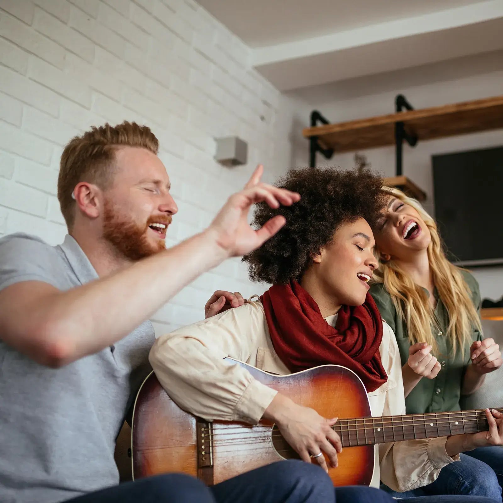 Friends singing and playing guitar together showcasing hearing aid music mode for enhanced audio quality