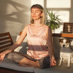 Woman meditating beside dog on sofa, suggesting tinnitus relief with ELEHEAR Beyond Pro hearing aids